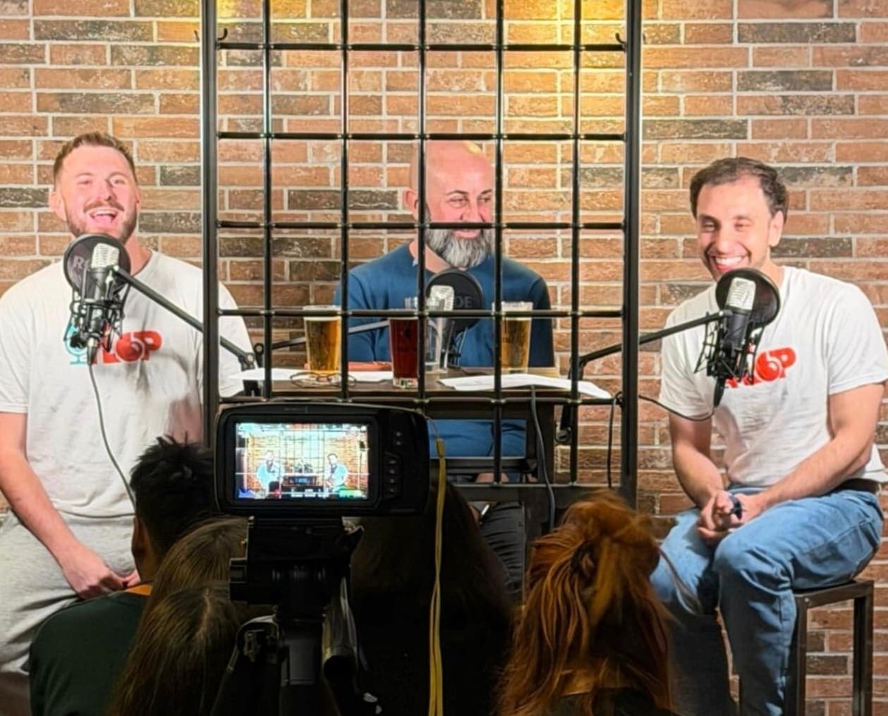 Tre ospiti ridono ai microfoni durante una serata dal vivo del podcast FLOP di Namo APS