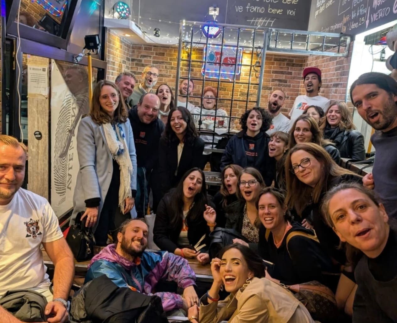 Foto di gruppo sorridente del pubblico a una serata del podcast FLOP organizzata da Namo APS