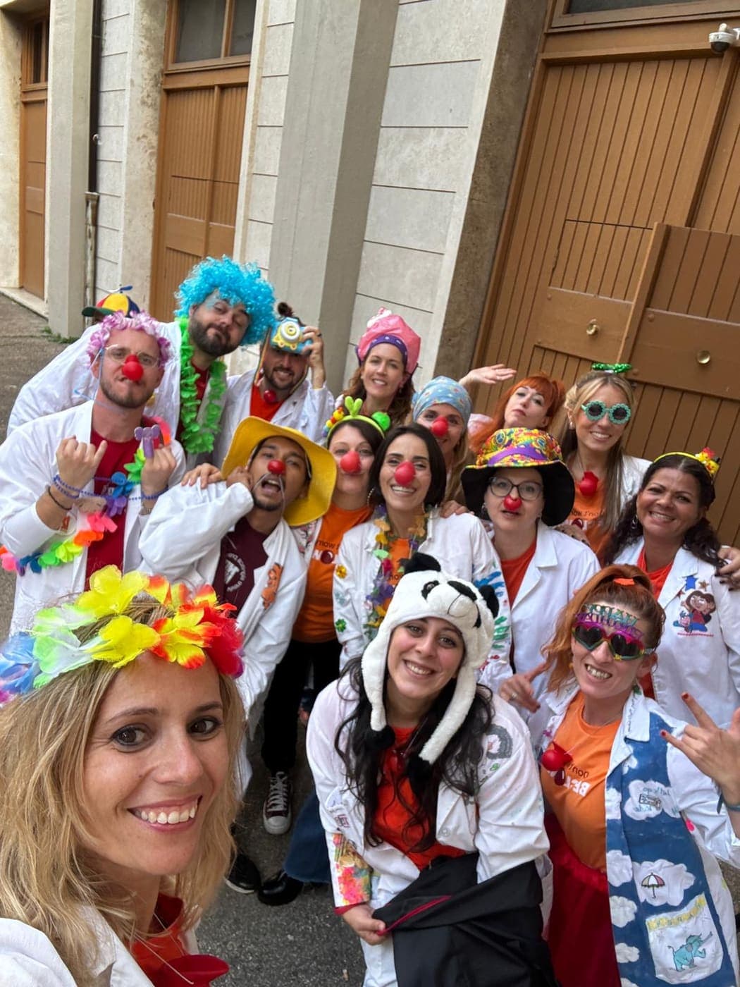 Selfie di gruppo dei volontari di Namo APS travestiti da clown, con nasi rossi, parrucche e cappelli colorati